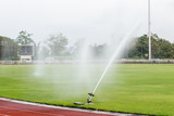 System working on fresh green grass on football or soccer stadium. Sprinkler watering field football. Automatic water irrigation in action. Close-up sprinkler of automatic watering. 