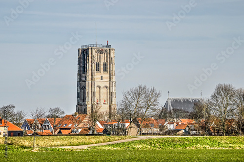 View of the town of Goedereede, The Netherlands from the surrounding green landscape, dominated by the church tower, seperated from the nave photo