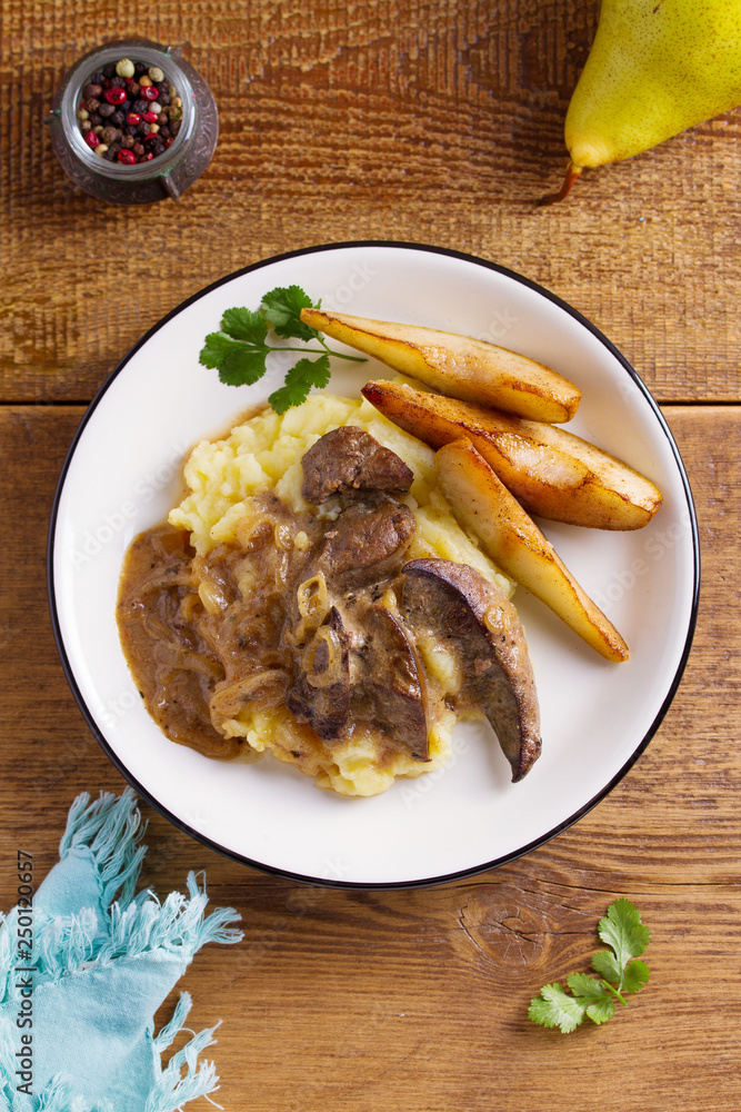 Beef liver with pears and mashed potato. View from above, top studio shot Beef liver with pears and mashed potato. View from above, top studio shot
