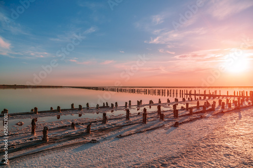 sunset on a pink salt lake, a former mine for the extraction of pink salt. row of wooden pegs overgrown with salt. © yelantsevv