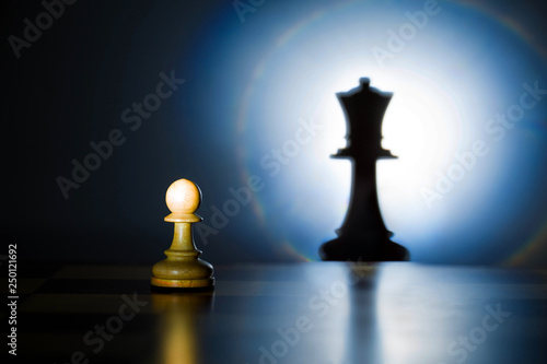 A pawn on a chessboard looks at its shadow of the future queen