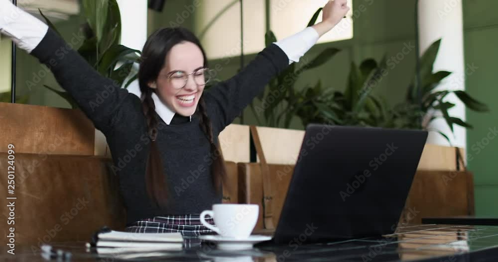 Portrait of student girl successfully raising hands up while working on laptop Portrait of student girl successfully raising hands up while working on laptop