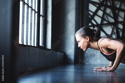 Athletic woman doing press-ups during the training in the health club.