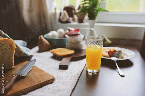 country cottage kitchen with breakfast on wooden table. Toast with jam, farm eggs and coffee