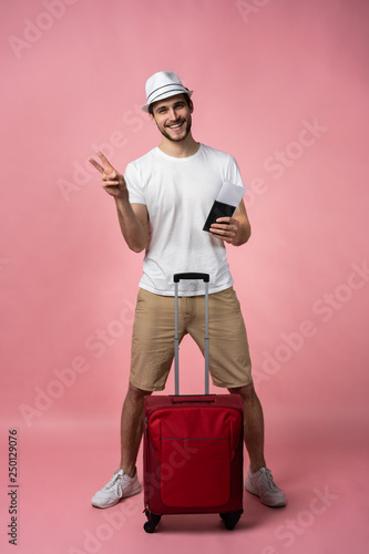 Man traveler with suitcase, passport and ticket on color background.