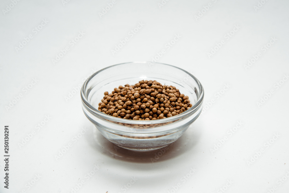 Coriander seeds on a white background in a bowl. Coriander placed on the table. The concept of using seasonings for dishes. Eating spiced dishes. Coriander seeds on a white background in a bowl. Coriander placed on the table. The concept of using seasonings for dishes. Eating spiced dishes.