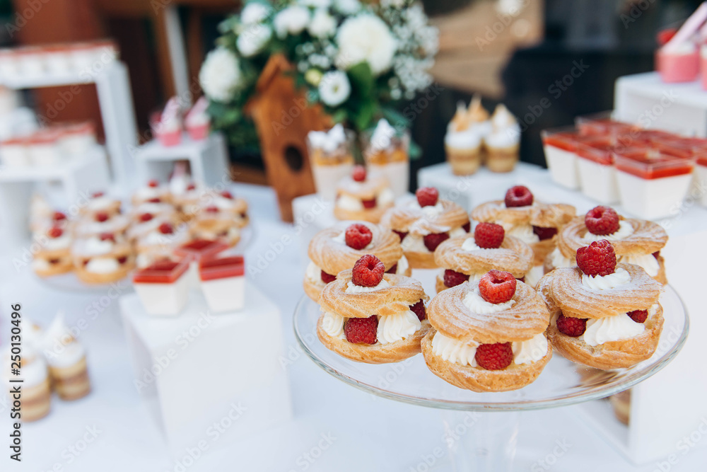 Sweet cake with raspberries and cream on beautiful wedding candybar background