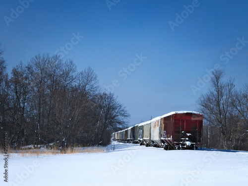 Snow covered railroad freight cars parked on rural side track on a cold winter day in Minnesota.