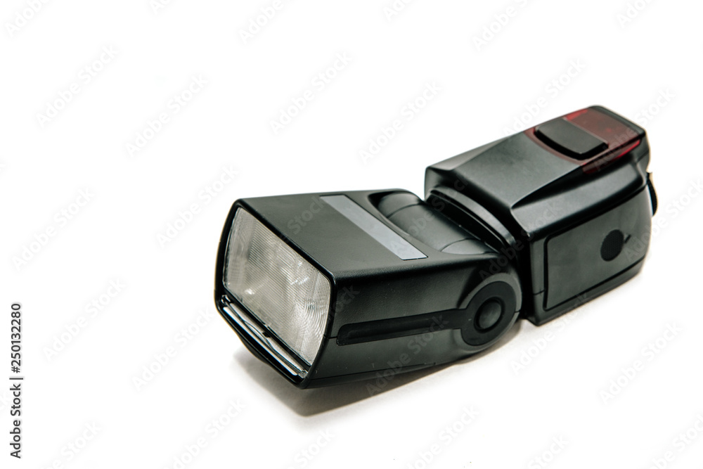 View of a black flash lamp isolated on a white background. The concept of triggering a flash for the camera. Adequate lighting during photography. View of a black flash lamp isolated on a white background. The concept of triggering a flash for the camera. Adequate lighting during photography.