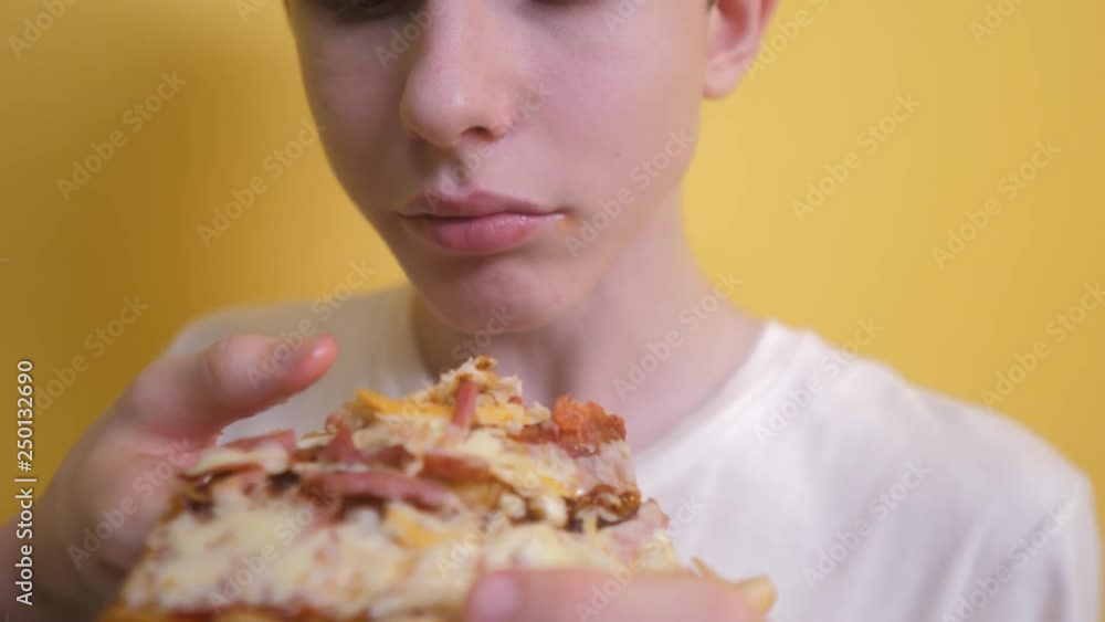 Pizza. happy teen boy eating a slice of pizza concept. teenage boy hungry eats a slice of pizza. slow motion video lifestyle . pizza fast food concept Pizza. happy teen boy eating a slice of pizza concept. teenage boy hungry eats a slice of pizza. slow motion video lifestyle . pizza fast food concept