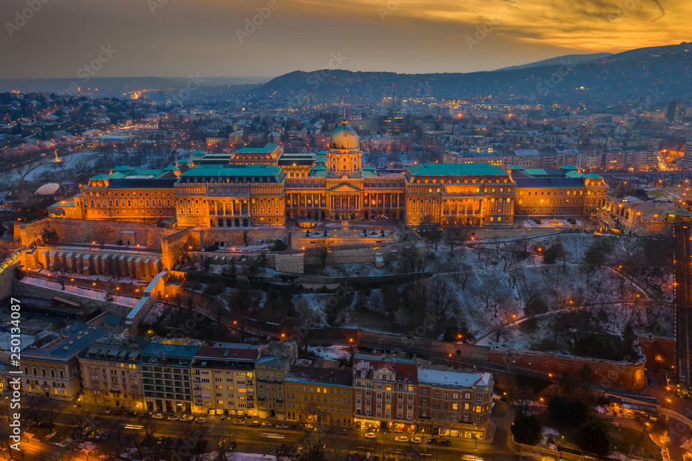 Budapest, Hungary - Aerial view of the snowy Buda Castle Royal Palace with beautiful golden sunset on a winter afternoon