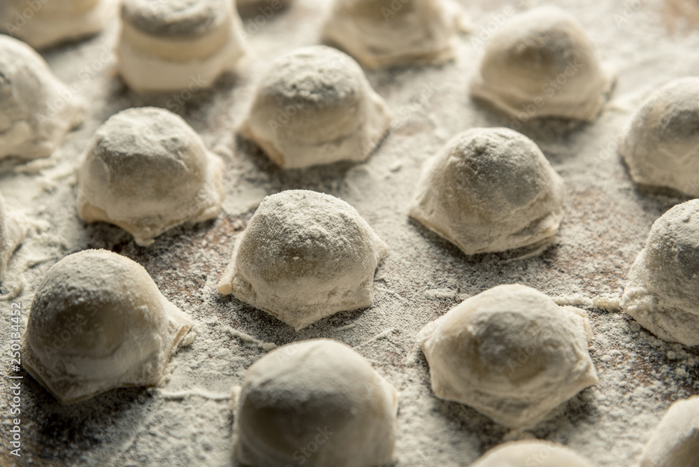 Uzbek national food Chuchvara, like dumplings, on a wooden board, in flour Uzbek national food Chuchvara, like dumplings, on a wooden board, in flour