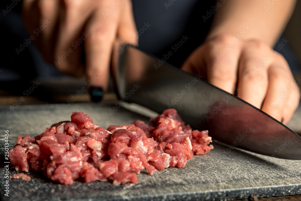 chef hands cut red meat on a board