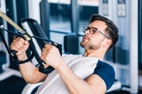 Focused athlete exercising with suspensions, close-up.