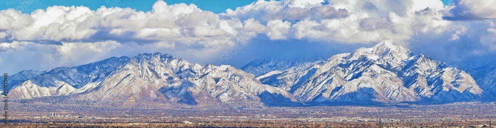 Winter Panoramic view of Snow capped Wasatch Front Rocky Mountains, Great Salt Lake Valley and Cloudscape from the Bacchus Highway. Utah, USA.