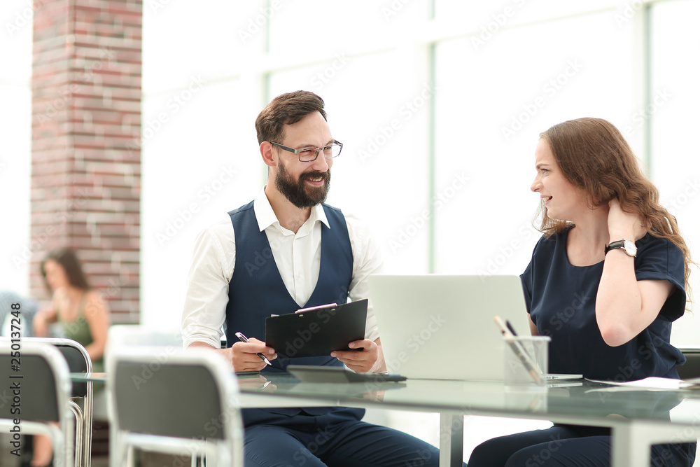 two employees discussing new ideas while sitting at the Desk two employees discussing new ideas while sitting at the Desk