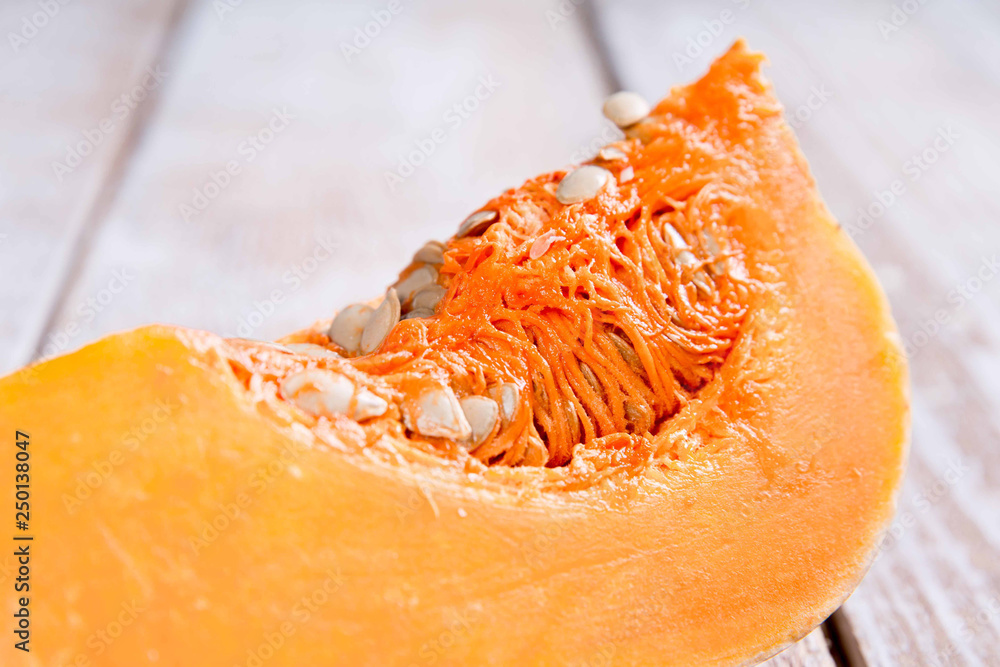 A fresh piece of pumpkin on a wooden background A fresh piece of pumpkin on a wooden background