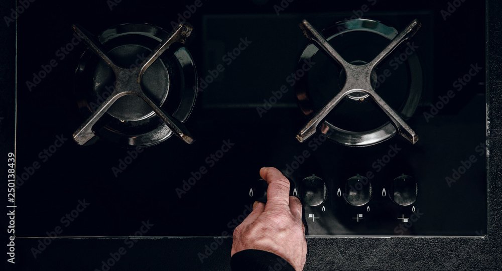 Top view of a man unscrewing a gas cock. Using a gas oven to prepare