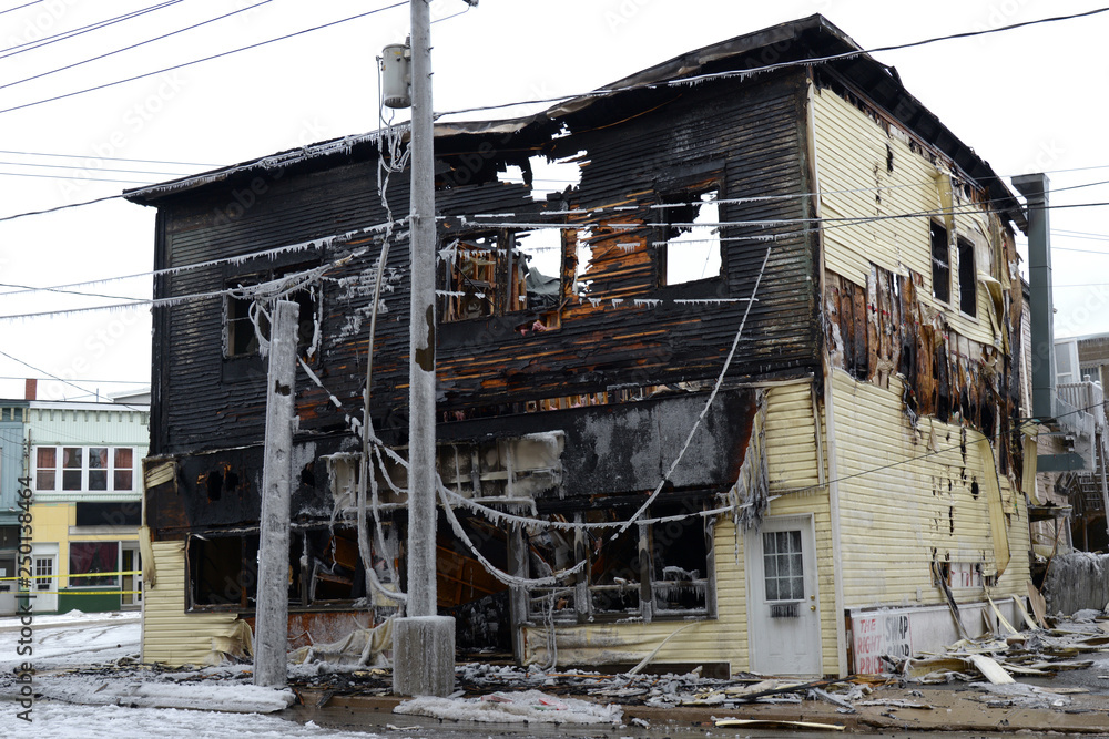 A burned building on a street corner in winter. The building is completely burned and looks like it will colapse. A burned building on a street corner in winter. The building is completely burned and looks like it will colapse.