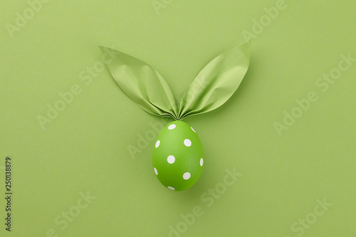 Photography Green dotted Easter egg with paper bunny ears, holiday concept