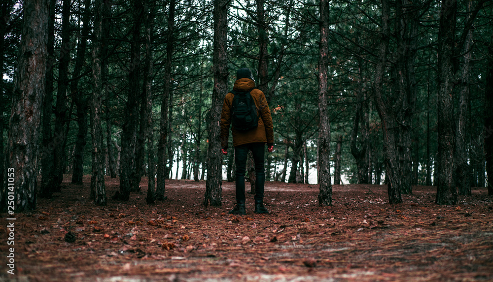 Young man walking through the dark autumn forest Young man walking through the dark autumn forest