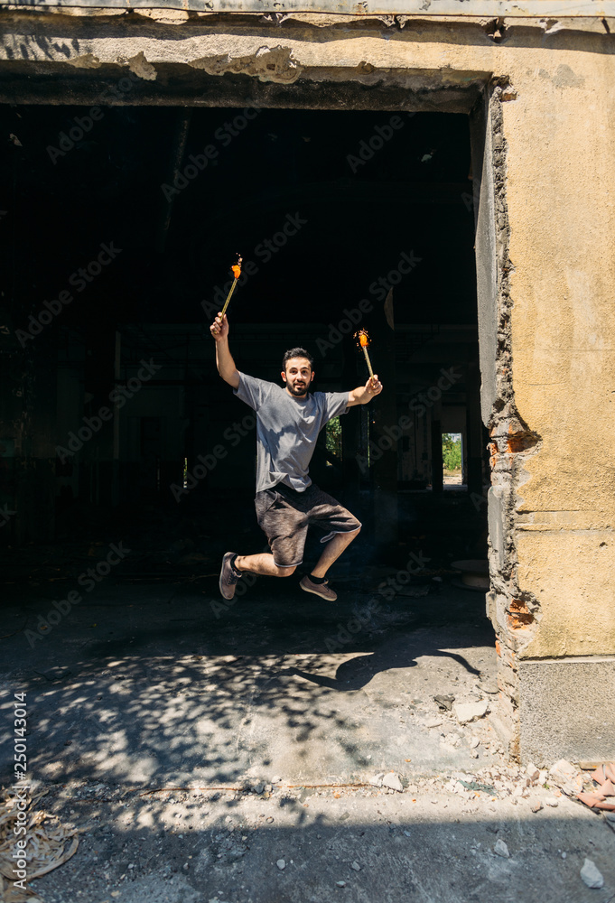 Man in abandoned factory with fireworks candle