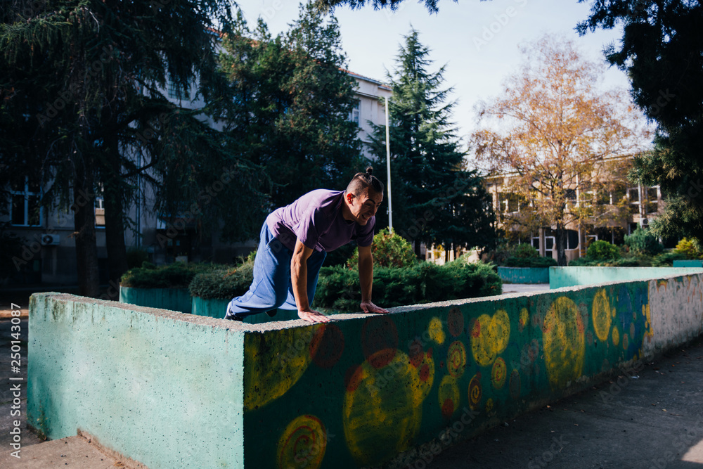Athletic Parkour guy doing backflip and tricks while jumping off and over .a concrete wall. Athletic Parkour guy doing backflip and tricks while jumping off and over .a concrete wall.