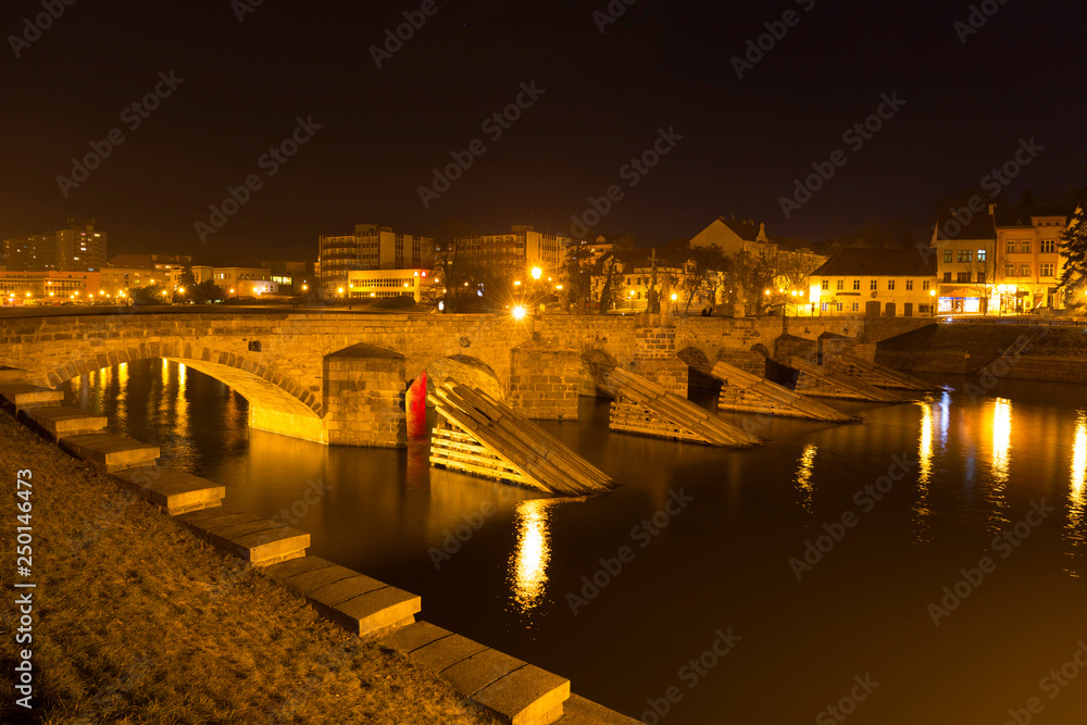 Night winter oldest stone bridge in central Europe above River Otava, Pisek, Czech Republic