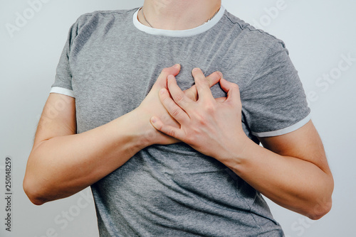 Myocardial infarction and heart problems. Medical and health concept. Man grasps his heart, holds his chest with his hand, and holds wall with other. Hypertension, high cholesterol.