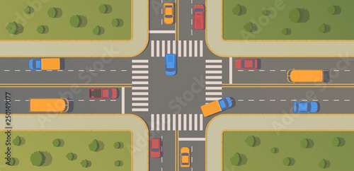Crossroads of two roads with pedestrian paths, curbs and boards, road markings, grass, bushes and trees.