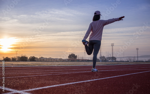 Pretty young girl doing sports on running tracks with pink cap and sweatshirt