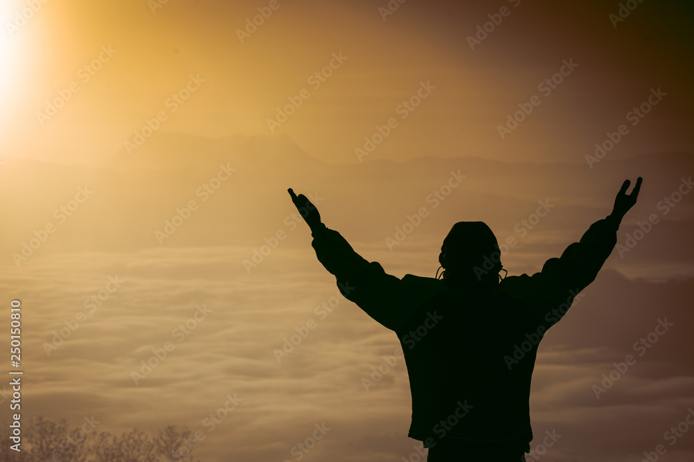 Man praying at sunset mountains raised hands Travel Lifestyle spiritual relaxation emotional concept, Freedom and travel adventure.