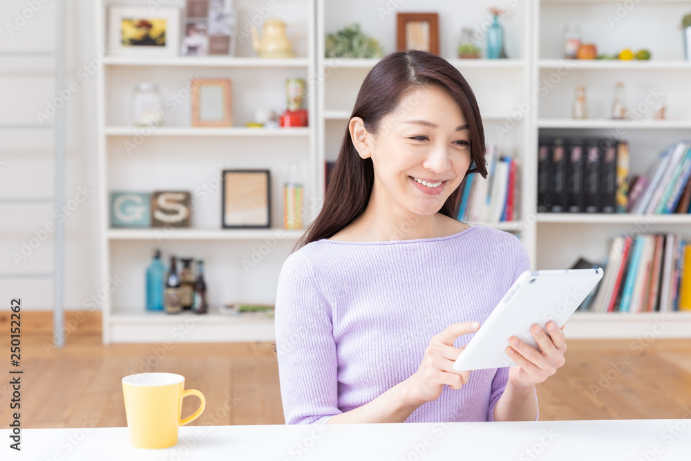 部屋でタブレットコンピューターを見る女性