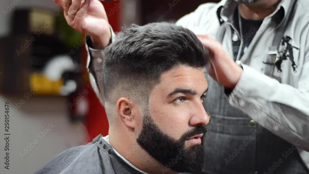 Barber using hair spray fixating hairdo at barber shop . Barber using hair spray fixating hairdo at barber shop .