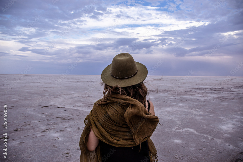 Kati Thanda Lake Eyre; woman in hat standing on salt lake looking out with clouds