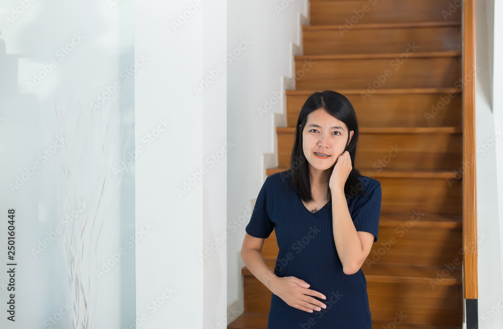 Asian beautiful pregnant woman standing with hand holding her belly at house,Happy mood and positive thinking