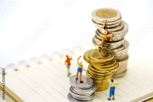 Miniature people climbing golden coins achieving top. Success, Finance, investment and growth in business concept.