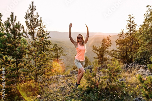 happy thirty-year-old woman standing at the top of the mountain