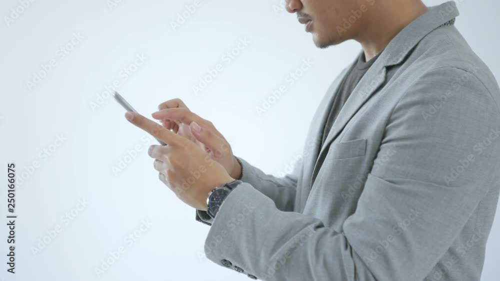 Attractive businessman standing , smiling, and checking his phone Attractive businessman standing , smiling, and checking his phone