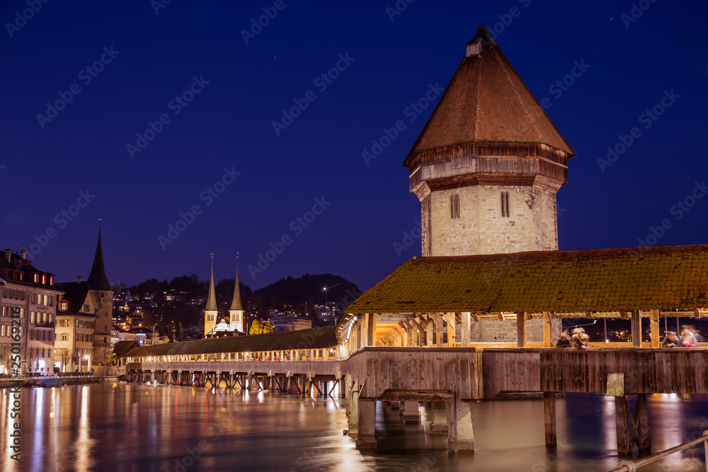 Chapel Bridge at night, wooden bridge with grand stone water tower - Luzern, Switzerland