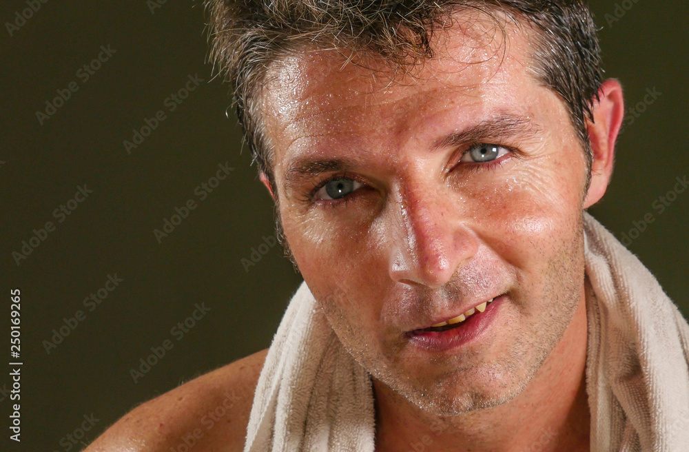 Obraz premium head and shoulders portrait of young attractive and handsome sport man sweating after gym workout training hard looking sweaty smiling happy with towel on his neck