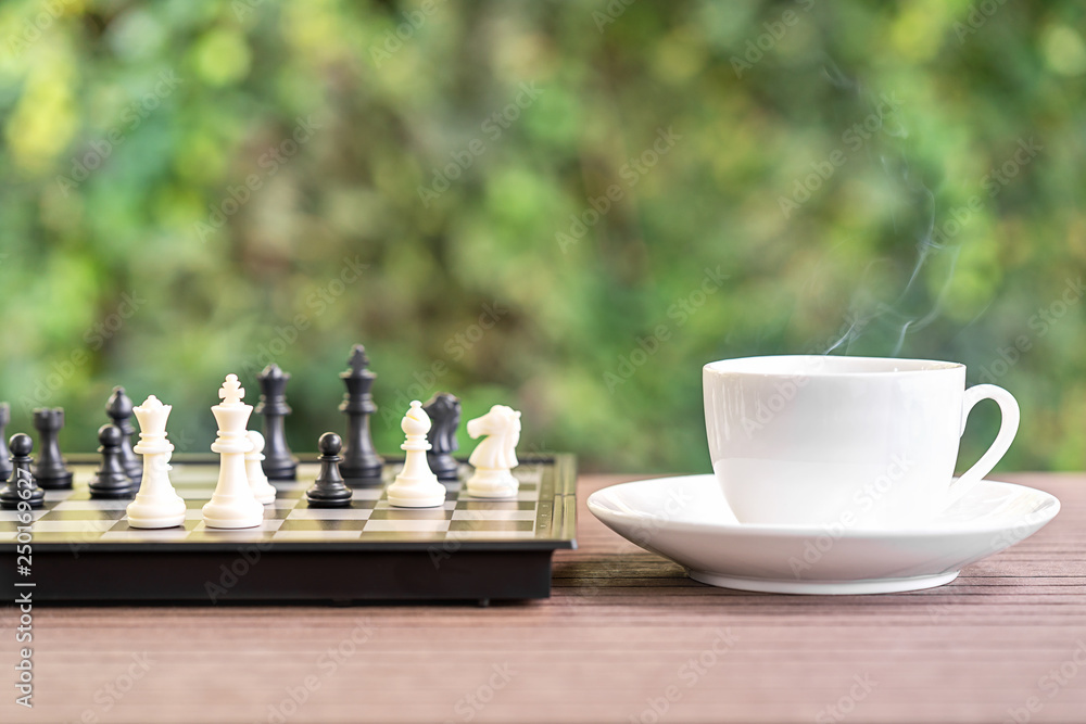 Obraz premium Coffee cup on wood table with Chess board
