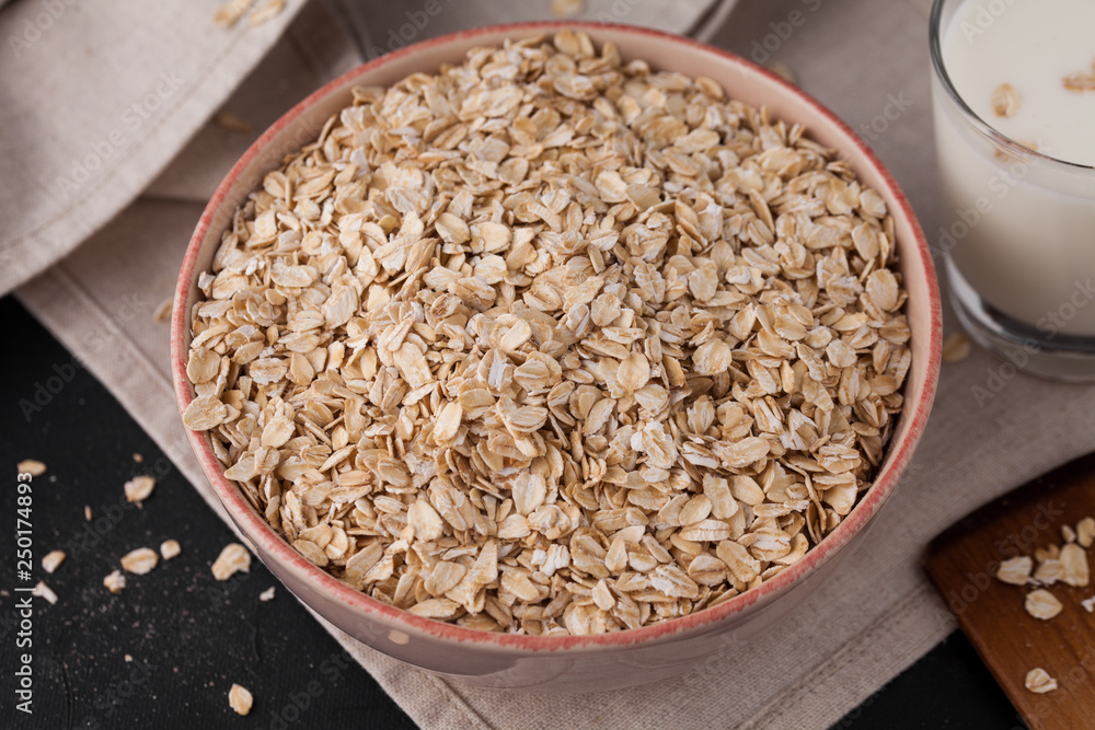 Oatmeal in a plate and a cup of milk on a towel on black background. Healthy food. close up Oatmeal in a plate and a cup of milk on a towel on black background. Healthy food. close up