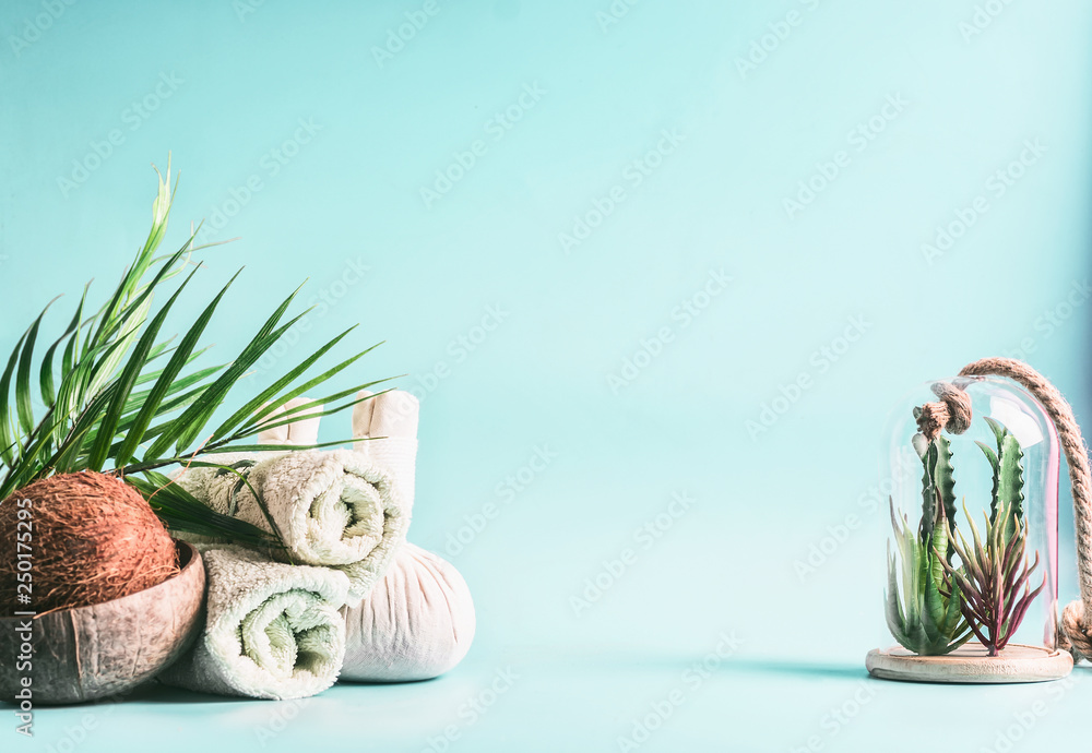 Spa background. Rolled towels, compress balls with coconut, palm leaves and  various succulent plants in glass at light blue background. Tropical  wellness and spa treatment. Body care concept Stock Photo | Adobe