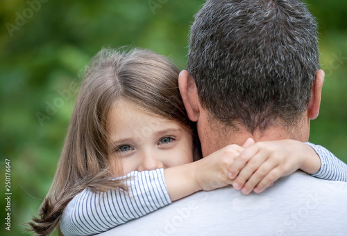 Portrait of cute little girl held in father's arms. Happy loving family. Father and his daughter child girl playing hugging. Cute baby and daddy. Concept of Father day. Family holiday and togetherness