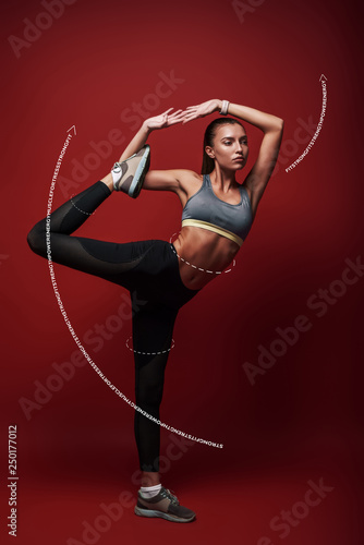 The best training program in the world is absolutely worthless without the will to execute it properly, consistently, and with intensity. Sportswoman standing over red background, stretching her body