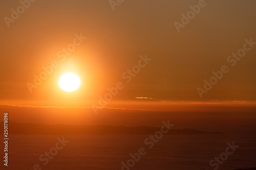 Beautiful sunset over a valley filled by fog with mountains and hills