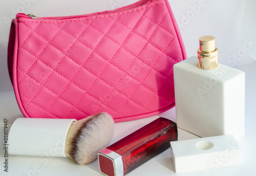 white tulip flower. pink cosmetic bag, makeup brushes, cosmetics on white background
