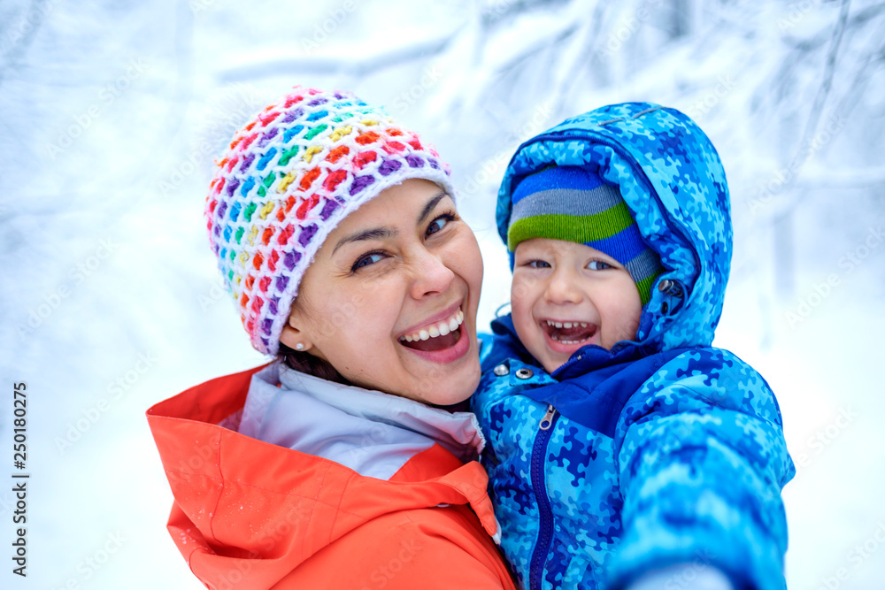 An Asian woman mother and her baby boy are playing in a snowy park in winter An Asian woman mother and her baby boy are playing in a snowy park in winter