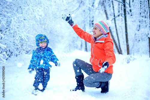 An Asian woman mother and her baby boy are playing in a snowy park in winter